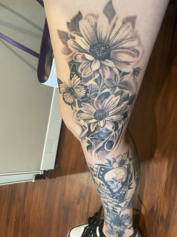 Black and grey floral and butterfly leg tattoo by Austina Obscure